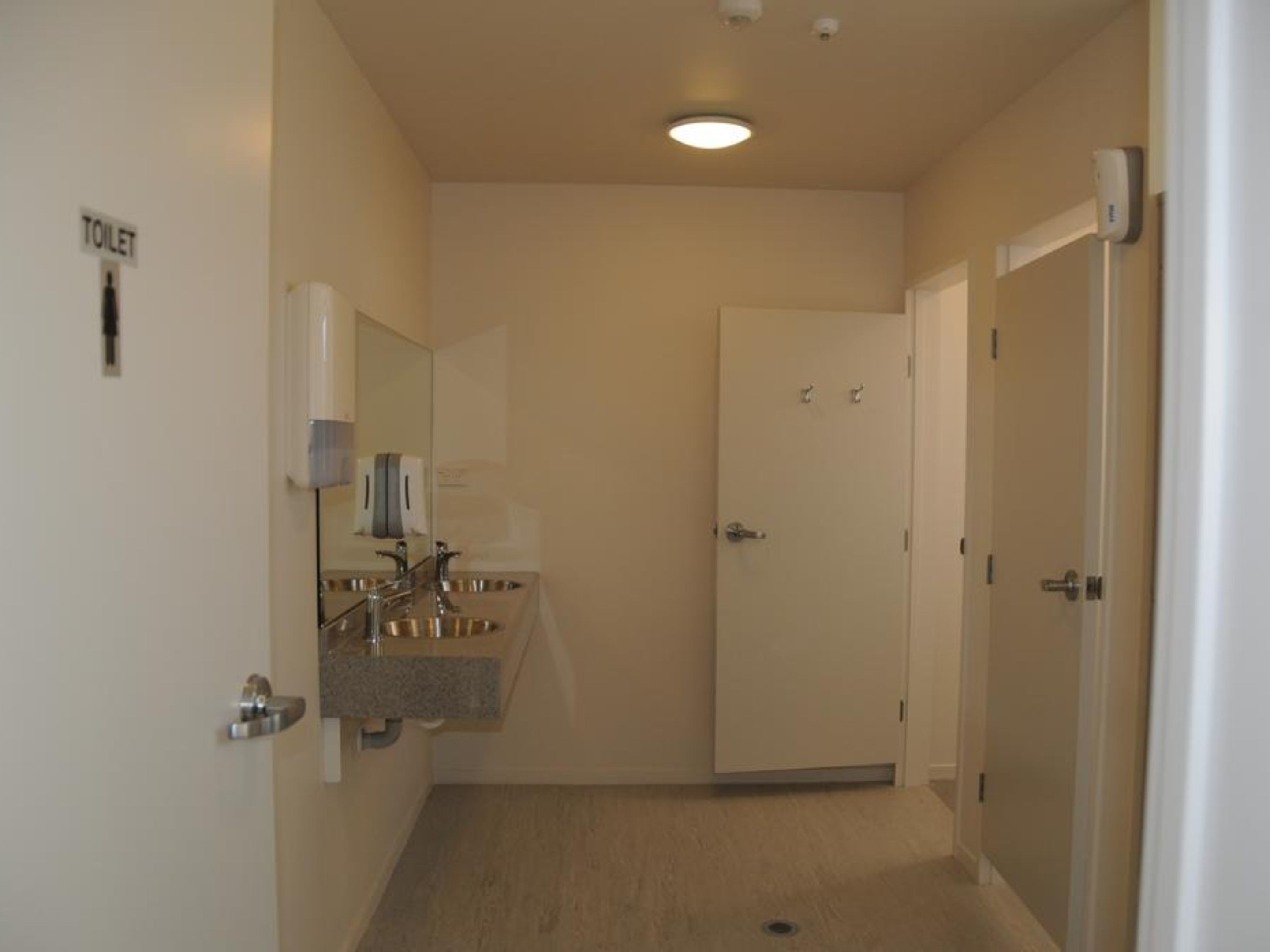 A small, narrow bathroom with a toilet, a sink, and a mirror.
