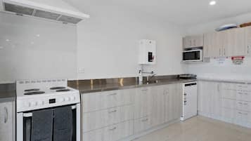 A modern kitchen with white cabinets, a stainless steel countertop, a built-in oven, and a microwave.