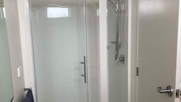 Une salle de bain moderne dotée d’une douche à parois de verre, de toilettes et d’un porte-serviettes.