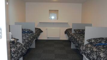 Un dormitorio con dos camas individuales, un radiador blanco y un espejo pequeño en la pared.