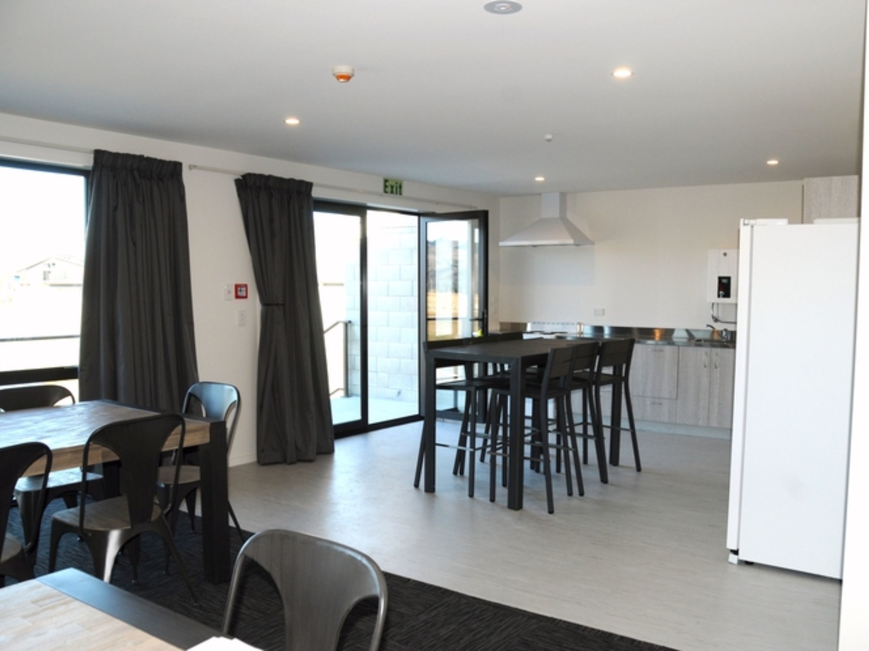 Una habitación de hotel moderna con comedor, cocina y un amplio ventanal con cortinas.