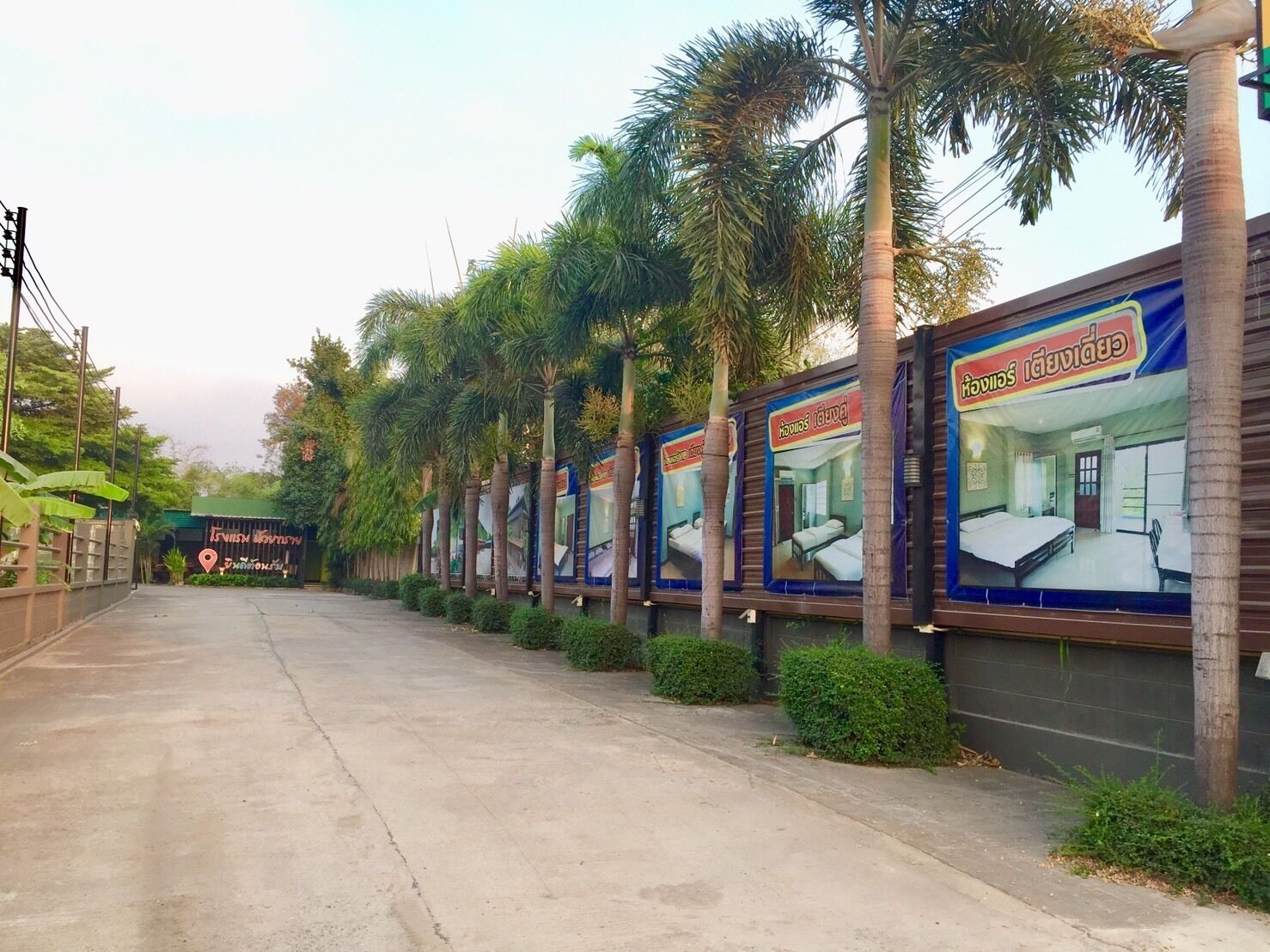 Una hilera de habitaciones con palmeras y un cartel que dice 'Hotel'.