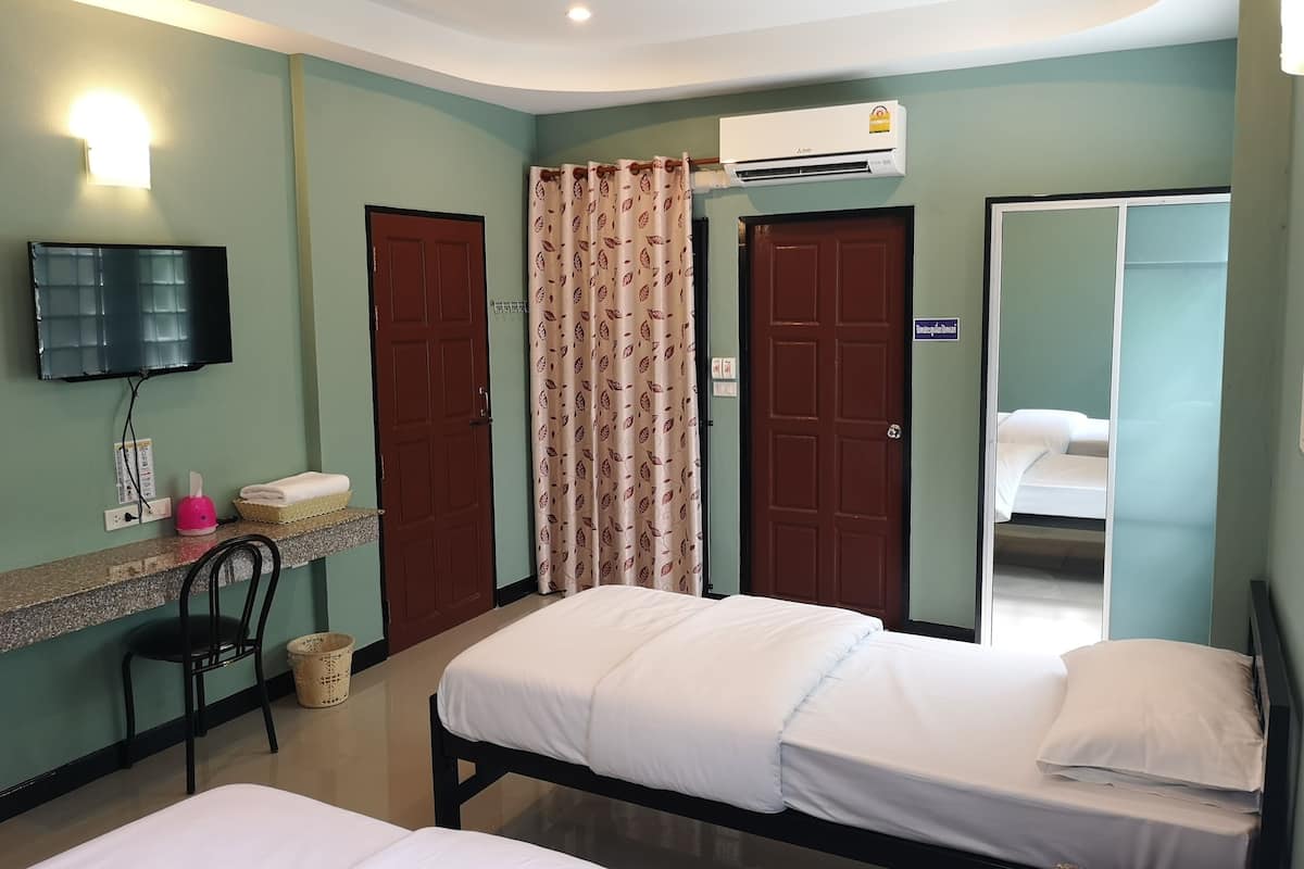 A hotel room with two beds, a TV, an air conditioner, and a mirror.