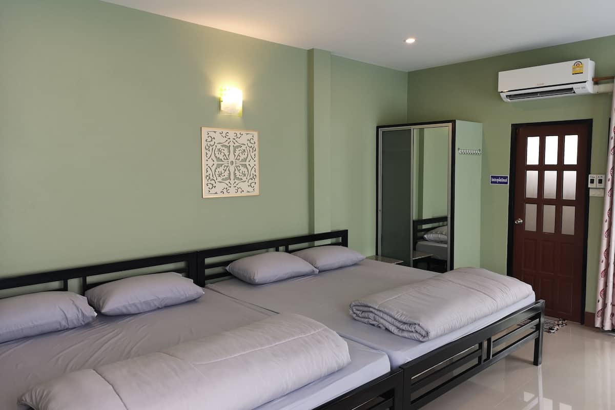 A hotel room with two beds, a wardrobe, an air conditioning unit, and a wall-mounted light fixture.