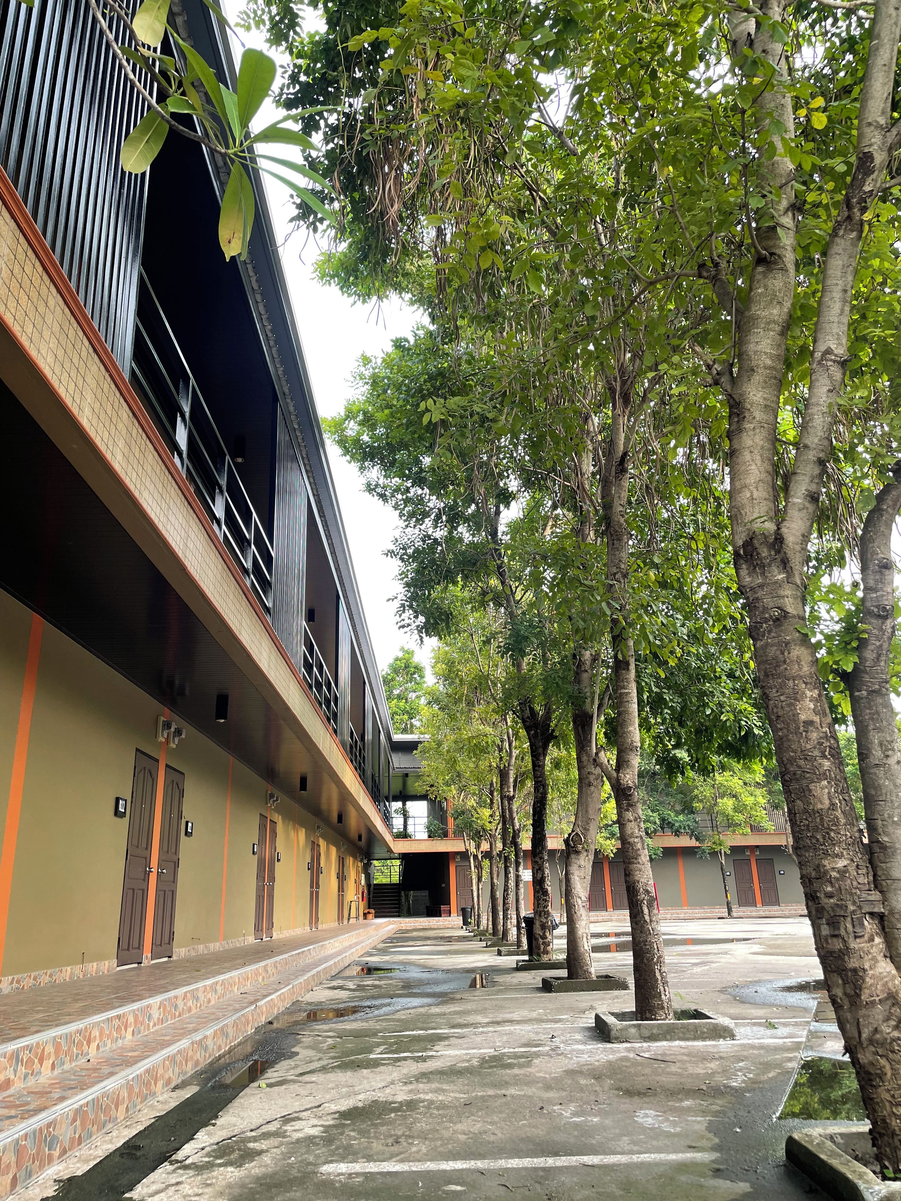 A building with multiple rooms, a covered walkway, and trees.
