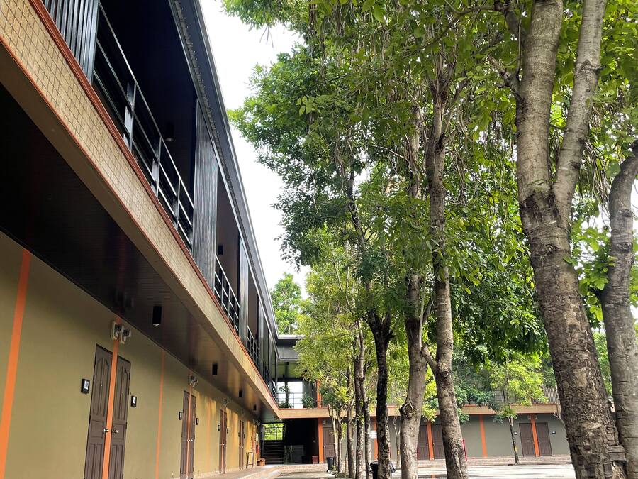 A building with multiple rooms, a covered walkway, and trees.