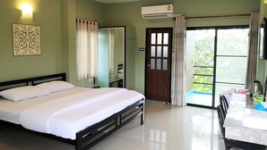 A hotel room with a bed, a desk, a chair, an air conditioning unit, and a view of the outdoors. - Huaisai Hotel (Nong Khae)