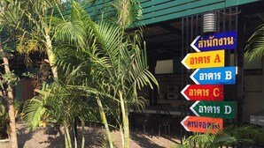 A signpost with multiple directional signs in a tropical setting. - Huaisai Hotel (Nong Khae)