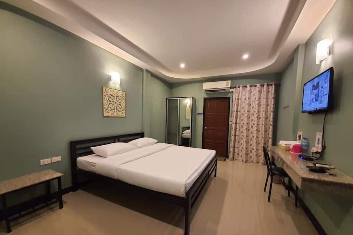 A hotel room with a bed, a desk with a chair, a television, and a wardrobe.