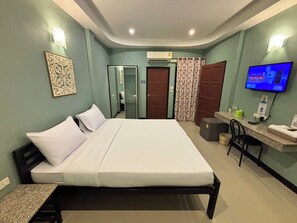 A hotel room with a bed, a desk, a chair, a television, and a bathroom visible through an open door. - Huaisai Hotel (Nong Khae)