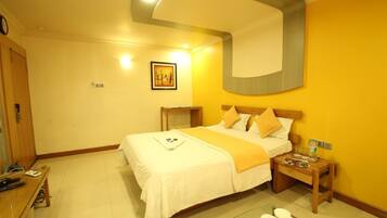 A hotel room with a bed, bedside tables, a desk, and a chair.