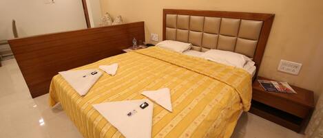 A hotel room with a bed, wooden headboard, and a nightstand with a magazine.