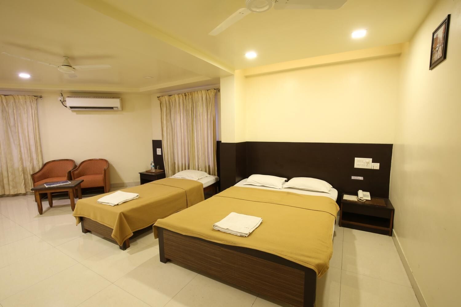 A hotel room with two single beds, a sofa, a small table, and a telephone.