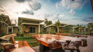 A resort with outdoor seating, palm trees, and a pool. - Green 2 (Chanthaburi)