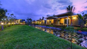 A modern hotel with a water feature and well-lit pathways. - Green 2 (Chanthaburi)