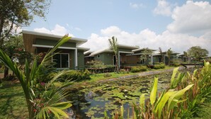 A modern hotel with a pool surrounded by lush greenery and a clear sky. - Green 2 (Chanthaburi)