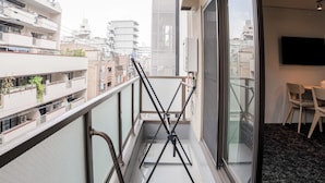 Un balcón con barandilla de metal, una puerta de vidrio y vistas a la ciudad.