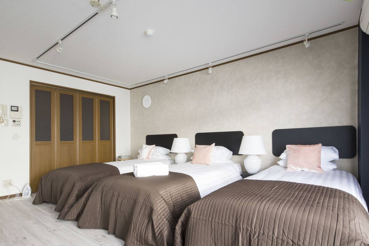 Habitación de hotel con dos camas, un armario de madera, un reloj en la pared y una lámpara en el techo.
