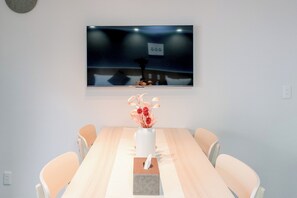 A conference room with a long table, four chairs, a vase with flowers, and a framed picture on the wall.