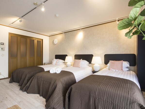 Ein Hotelzimmer mit zwei Betten, jeweils mit Kopfteil, Nachttischlampen und einer Wanduhr.