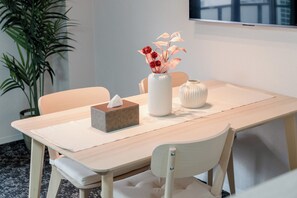 A dining table with a tissue box, a vase with flowers, and a decorative bowl.