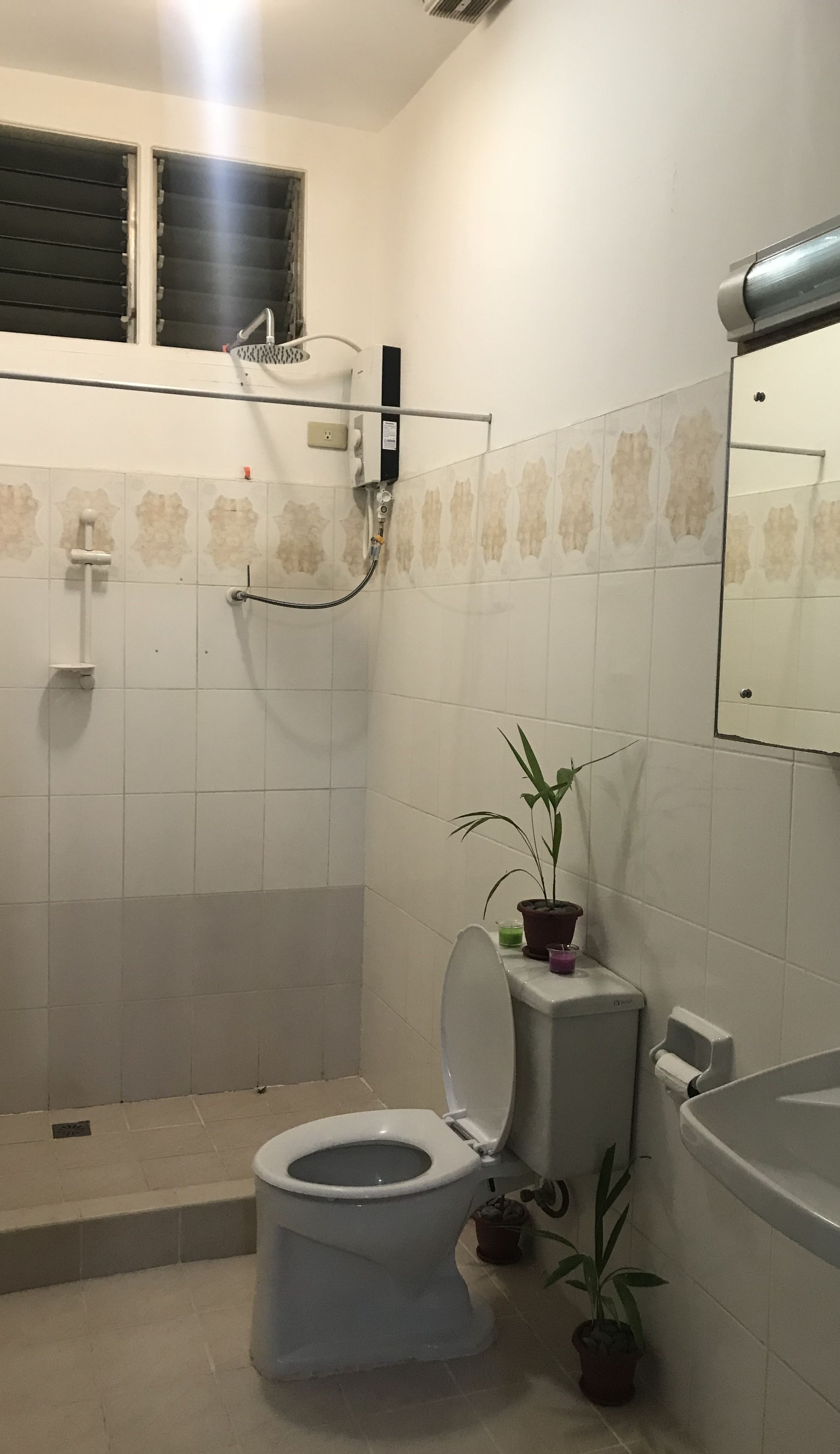 Et badeværelse med toilet, bruser og håndvask.