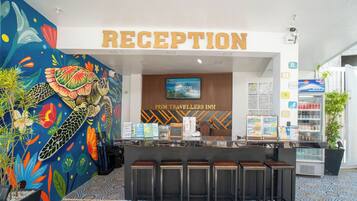 Zona de recepción con un mural colorido, un cartel que dice "RECEPTION" y un mostrador con folletos informativos.