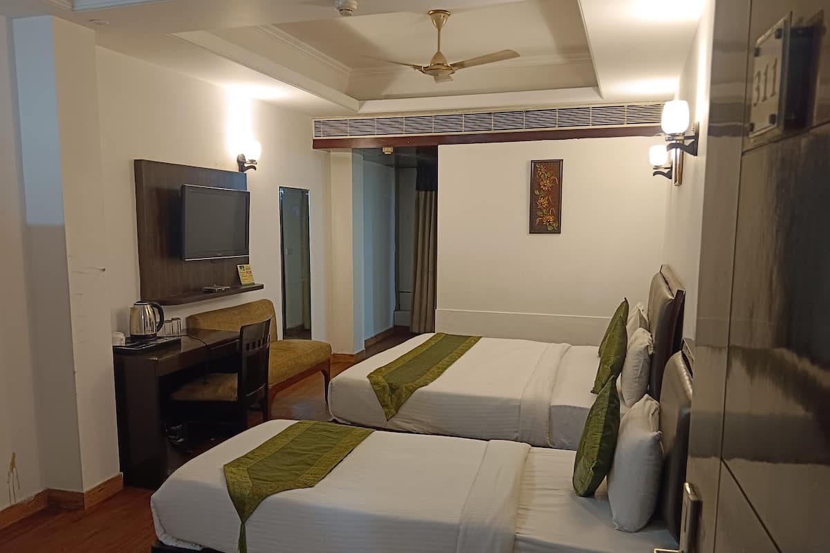 A hotel room with two beds, a television, a desk with a chair, and a wardrobe.