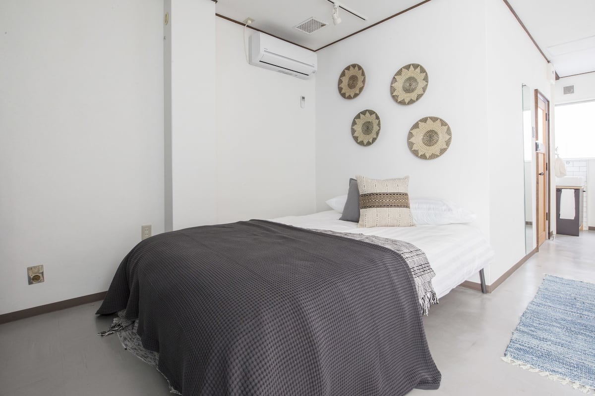 A modern bedroom with a bed, a large window, and a ceiling fan.