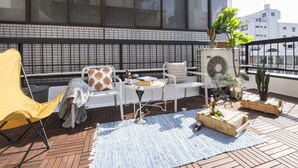 A rooftop terrace with a seating area, a yellow chair, a small table, and a potted plant. - nid NAMBA Station House (Osaka)