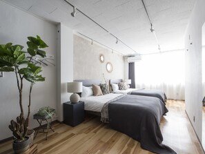 A modern bedroom with two beds, a large potted plant, a mirror, and a wall-mounted air conditioner. - nid NAMBA Station House (Osaka)