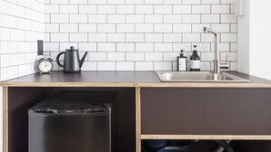 A kitchen with white subway tiles, a black coffee maker, a sink, and a dishwasher. - nid NAMBA Station House (Osaka)