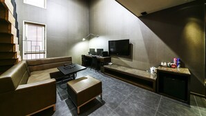 A modern living room with a sofa, a coffee table, a TV, and a small entertainment unit. - Arrietty Motel (Gyeongju)