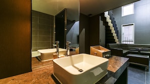 A modern bathroom with a large white sink, a mirror, and a dark tiled wall. - Arrietty Motel (Gyeongju)