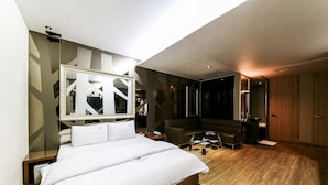 A modern hotel room with a large bed, a seating area, a mirror, and a wardrobe. - Arrietty Motel (Gyeongju)