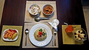 Uma mesa posta com um prato de comida, duas tigelas de acompanhamentos, um copo de bebida e uma colher.