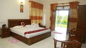 A bedroom with a wooden bed, a nightstand, a chair, and a view of the outdoors through a glass door. - Villa A.SMS (Induruwa)
