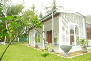 A modern house with a covered porch, a large planter, and a lawn. - Villa A.SMS (Induruwa)