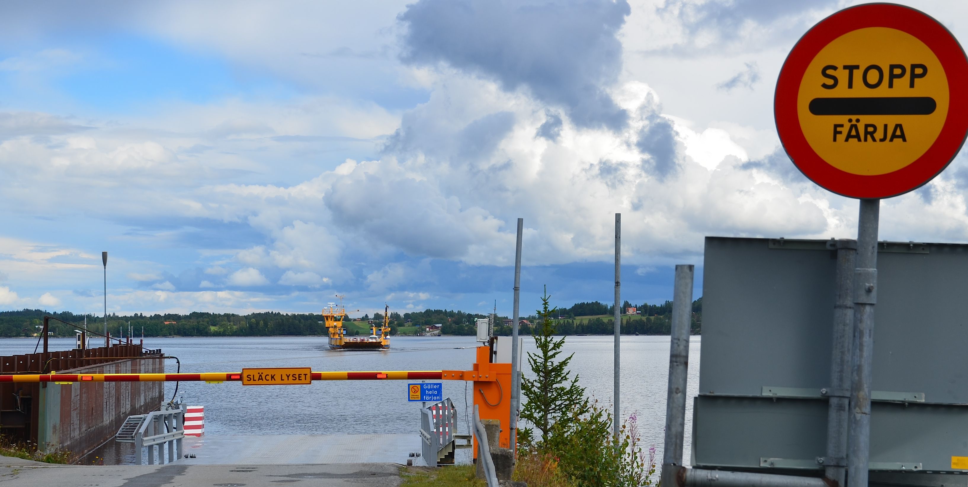 Sataman sisäänkäynti, jossa on stop-merkki, sulkuportti ja taustalla näkyvä laiva.
