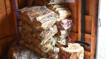 A storage area with stacks of burlap sacks containing logs, a saw, and a sign with text.