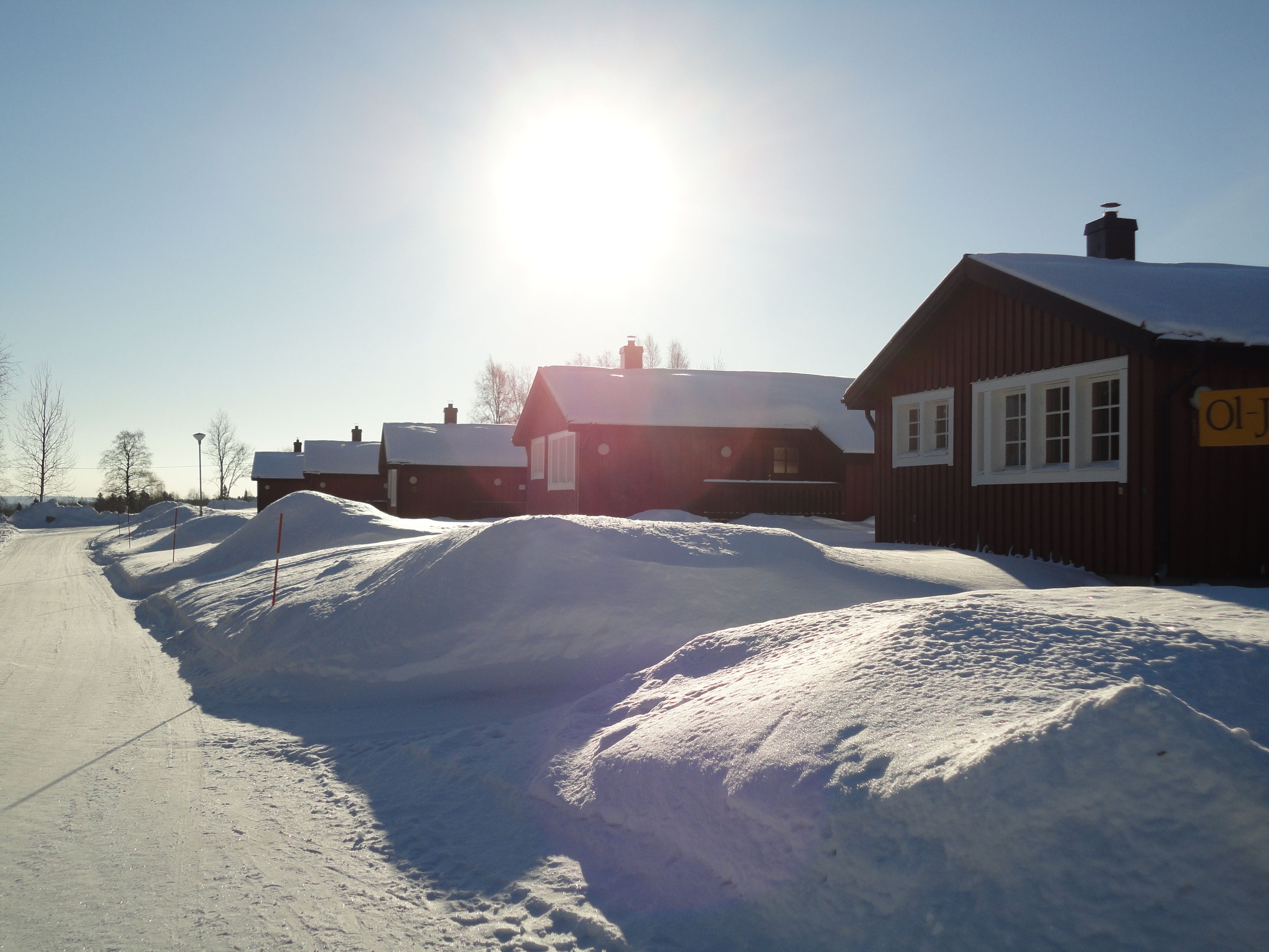 Ett snötäckt landskap med en träbyggnad och en väg.