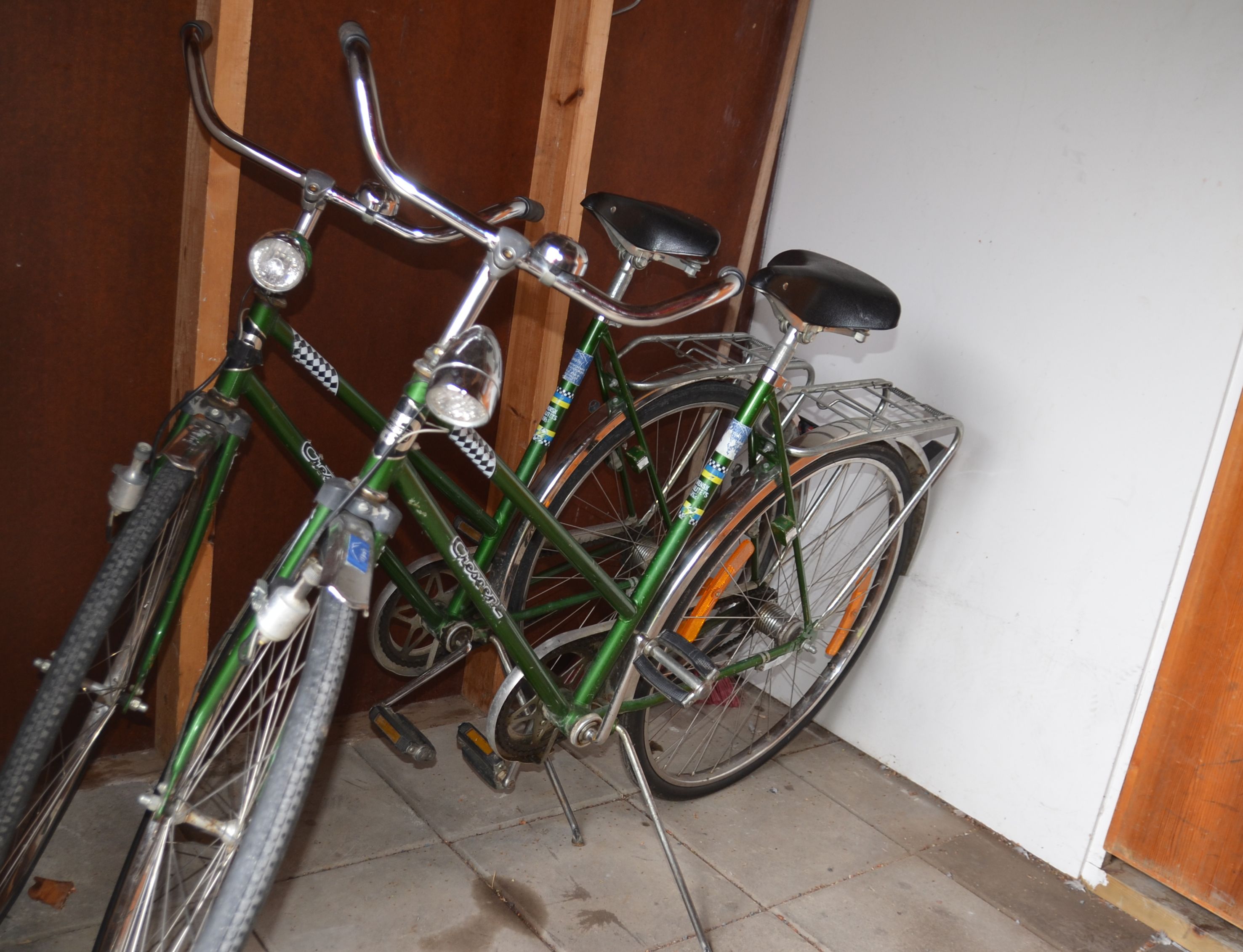 Una bicicleta apoyada en una puerta de madera, con un portaequipajes metálico fijado a la pared.