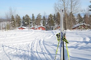 A snowy landscape with red wooden cabins and a ski pole. - Ol-jons By (Hallen)