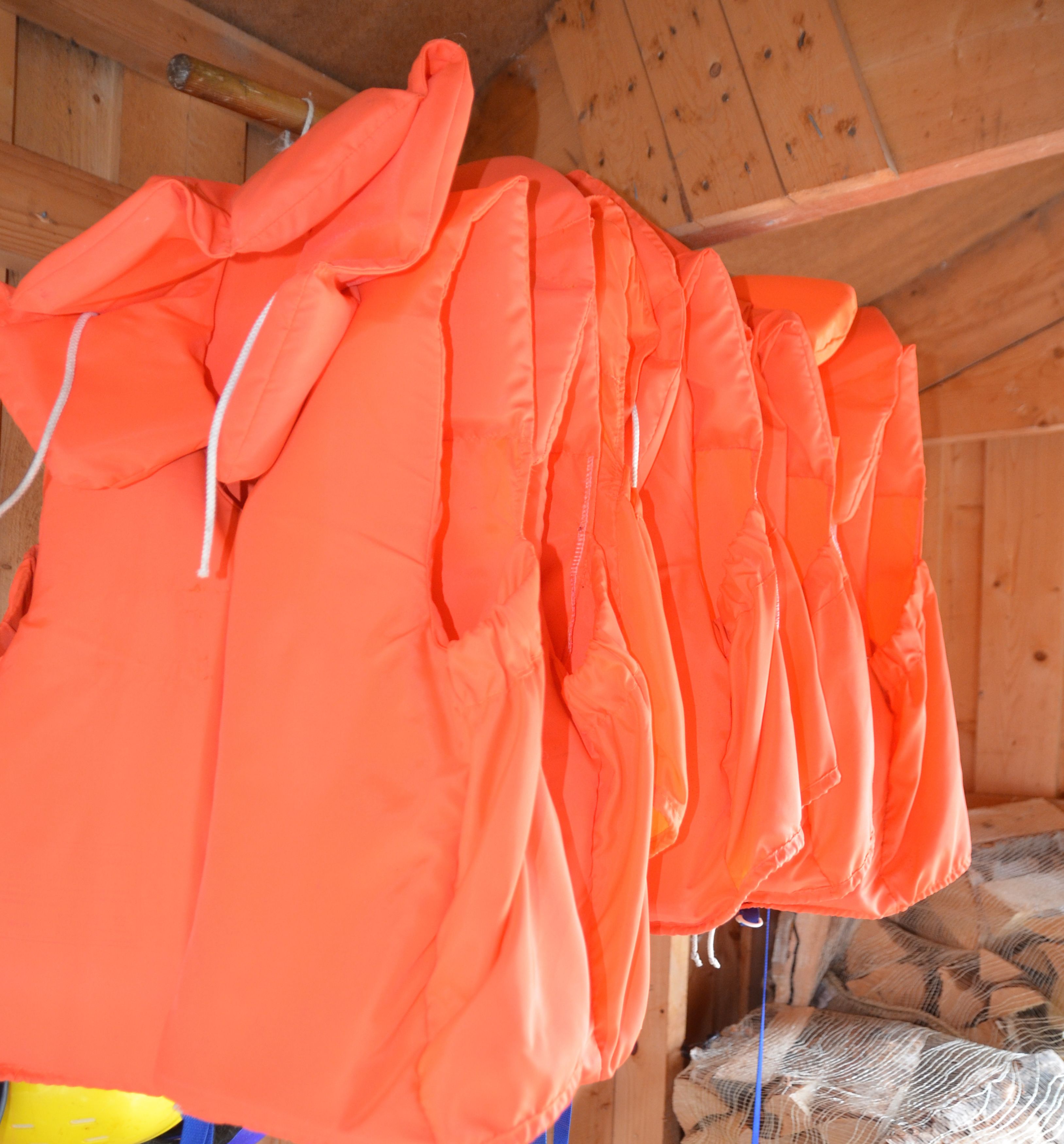 A wooden interior with orange jackets hanging on a rack.