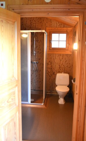 A small bathroom with a shower, toilet, and a window. - Ol-jons By (Hallen)