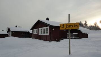 Une cabane en bois recouverte de neige, sur laquelle on peut lire l’inscription : « Ol-Jons ».