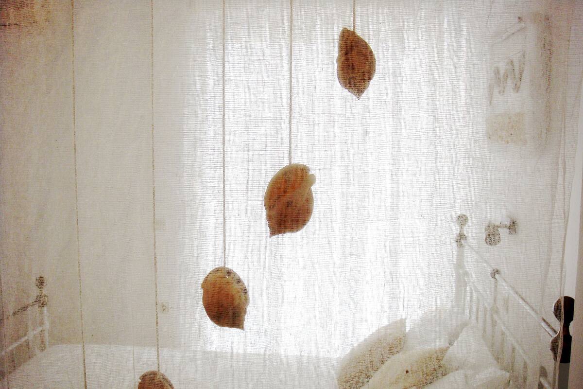 Quarto com cama branca, cabeceira de madeira e luminária pendente.