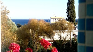 A garden with pink flowers and a view of a building with a white facade and a yellow roof. - Blugreen Stegna B&B (Rhodes)