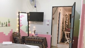 A bedroom with a bed, a desk, a chair, a TV, and a fan. - Hani House (Pleiku)