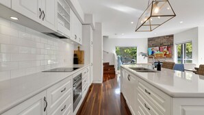 A modern kitchen with white cabinetry, a black countertop, and a wooden floor. - Beyond Bliss - Guesthouse 1 (BRIGHT)